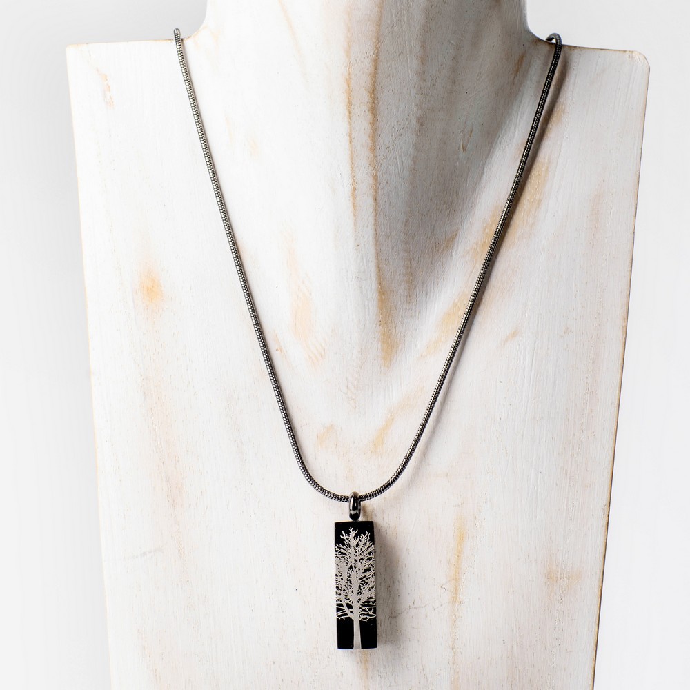 Cremation keepsake pendant on a silver chain featuring a rectangular black graphite tree root charm.