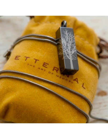 Cremation Jewell Tree Root Graphite Pendant by Etternal on a mustard pouch with the tree root design visible on the rectangular