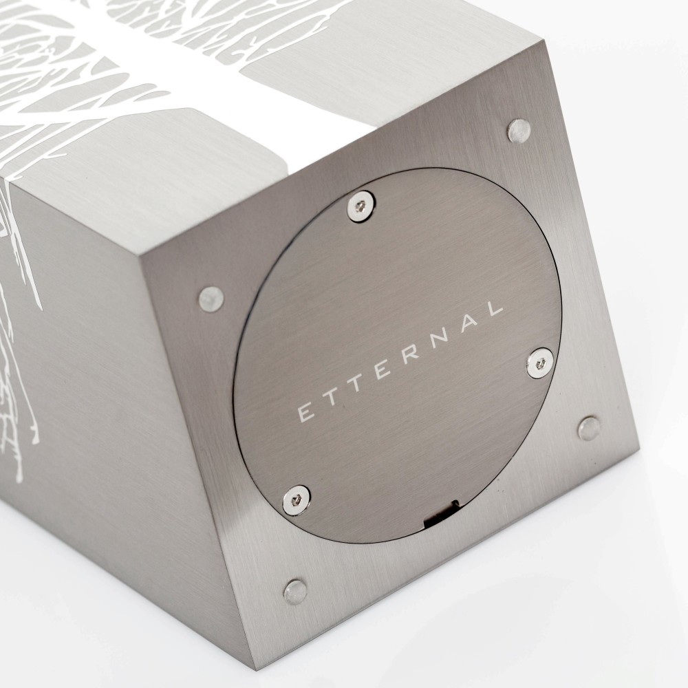Cremation Urn Tree Root by Etternal Arte Funerario: brushed metal cube with round access plate labeled ETTERNAL on side, white t